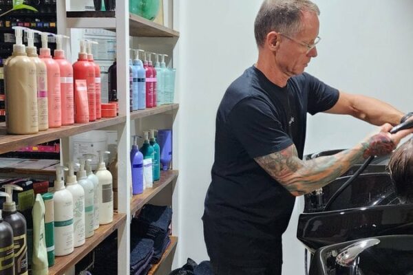 Dj washing clients hair in shampoo bowl